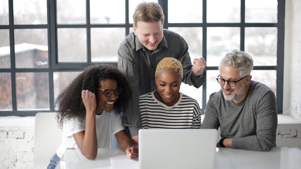 Group of coworkers around a laptop.